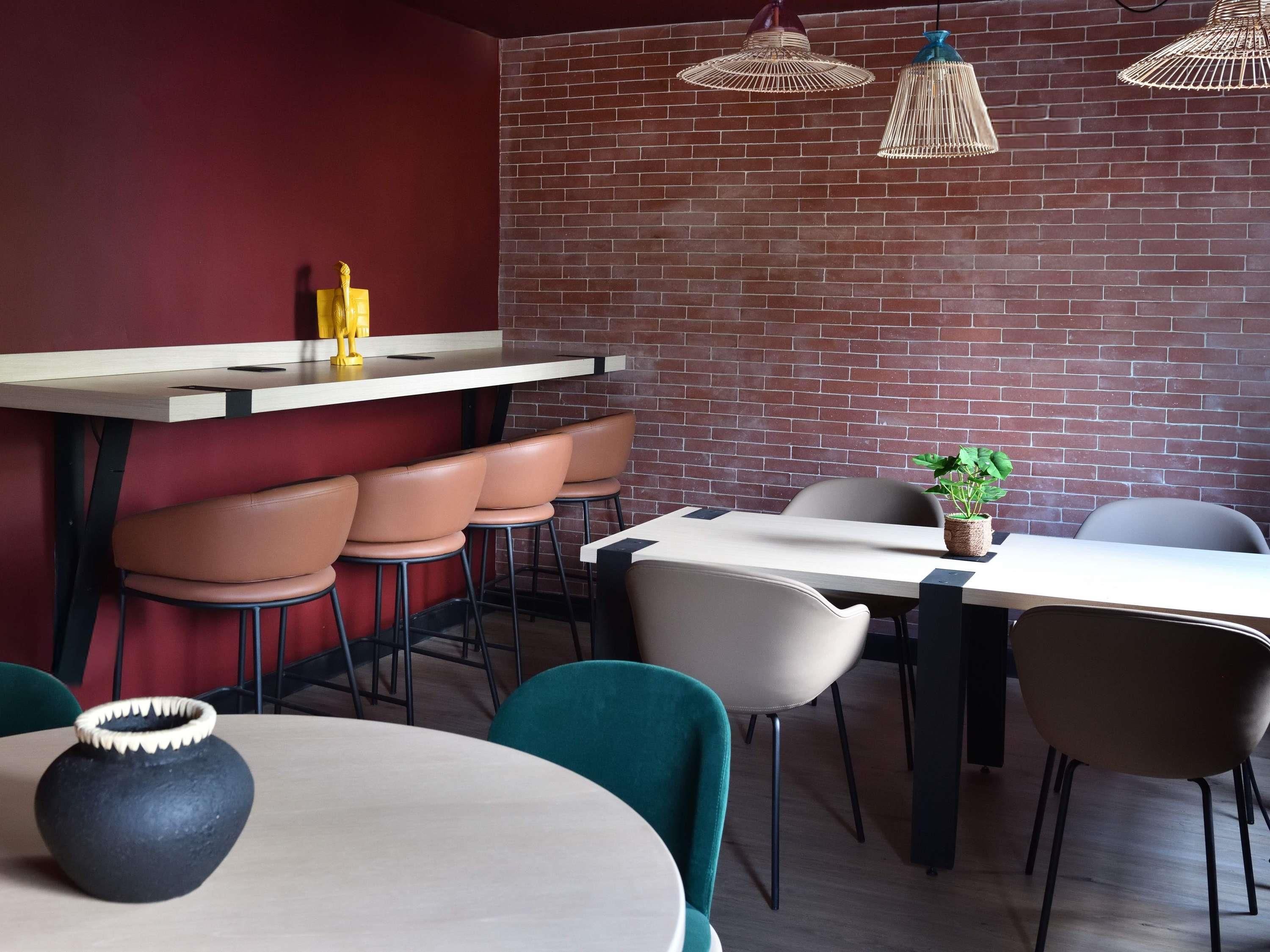 A modern dining area with a brick wall, wooden tables, and chairs.