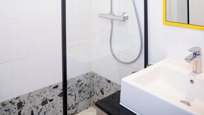 A modern bathroom with a glass-enclosed shower, a white sink, and a mirror with a yellow frame. - ibis Styles Abidjan Marcory (Abidjan)