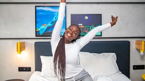 Una habitación de hotel con una cama, una mesita de noche y una lámpara fijada a la pared.