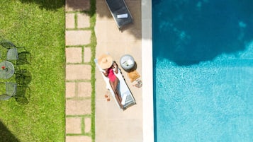 Relax by the pool surrounded by a tranquil outdoor space with a sun lounger and casual seating area.