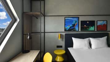Una habitación de hotel moderna con una cama, un escritorio, una silla y una ventana con vista a la ciudad.