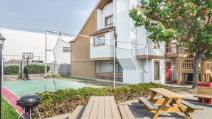 Um edifício residencial com quadra de basquete, área de estar externa e churrasqueira.