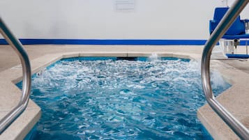 A swimming pool with clear water, a blue and white wall, and a metal pool ladder.
