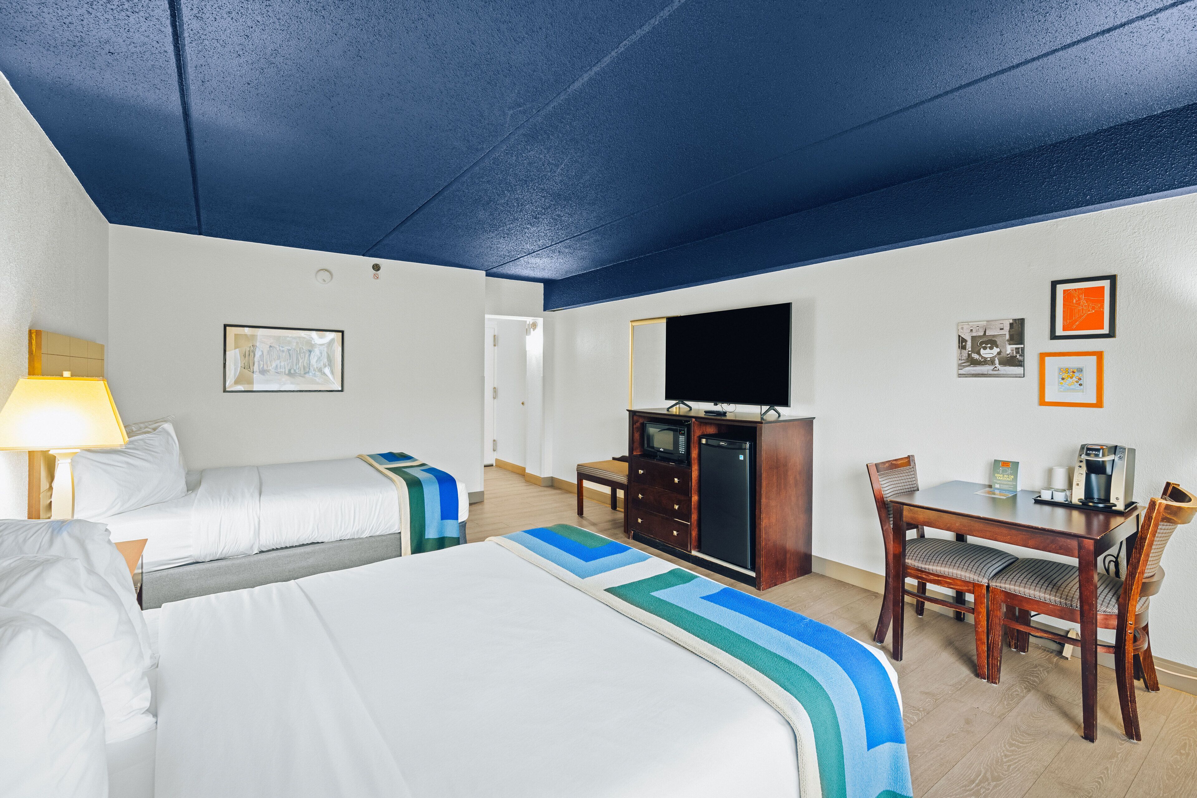 Een hotelkamer met twee bedden, een bureau met stoel, een televisie en een magnetron.