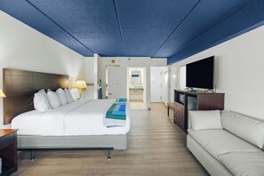 A hotel room with a bed, a sofa, a TV, and a bathroom visible through an open door. - Hotel Downstreet, an Ascend Collection Hotel (North Adams)