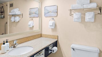 A bathroom with a sink, mirror, towel racks, and a toilet.