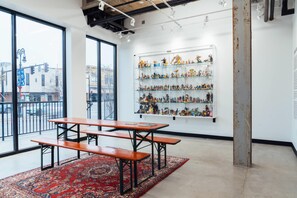 A room with large windows, a red patterned rug, a wooden table with benches, and shelves with figurines. - Hotel Downstreet, an Ascend Collection Hotel (North Adams)