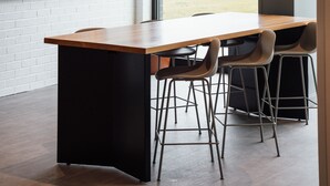 A modern interior with a large window, a wooden table, and bar stools.