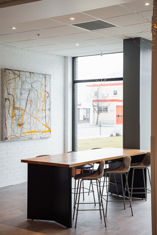 A modern interior with a large window, a wooden table, and bar stools. - Hotel Downstreet, an Ascend Collection Hotel (North Adams)