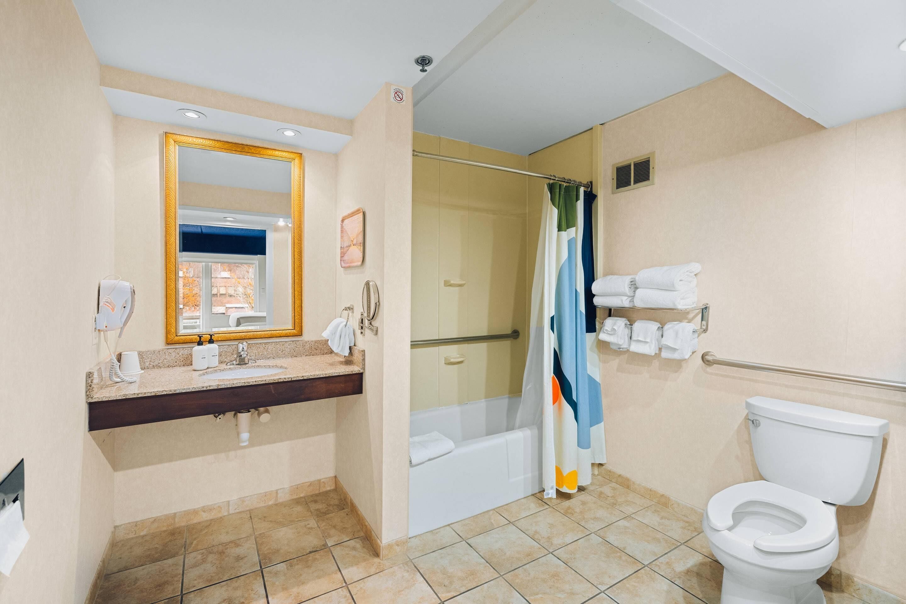 A bathroom with a sink, mirror, shower, toilet, and towel rack.