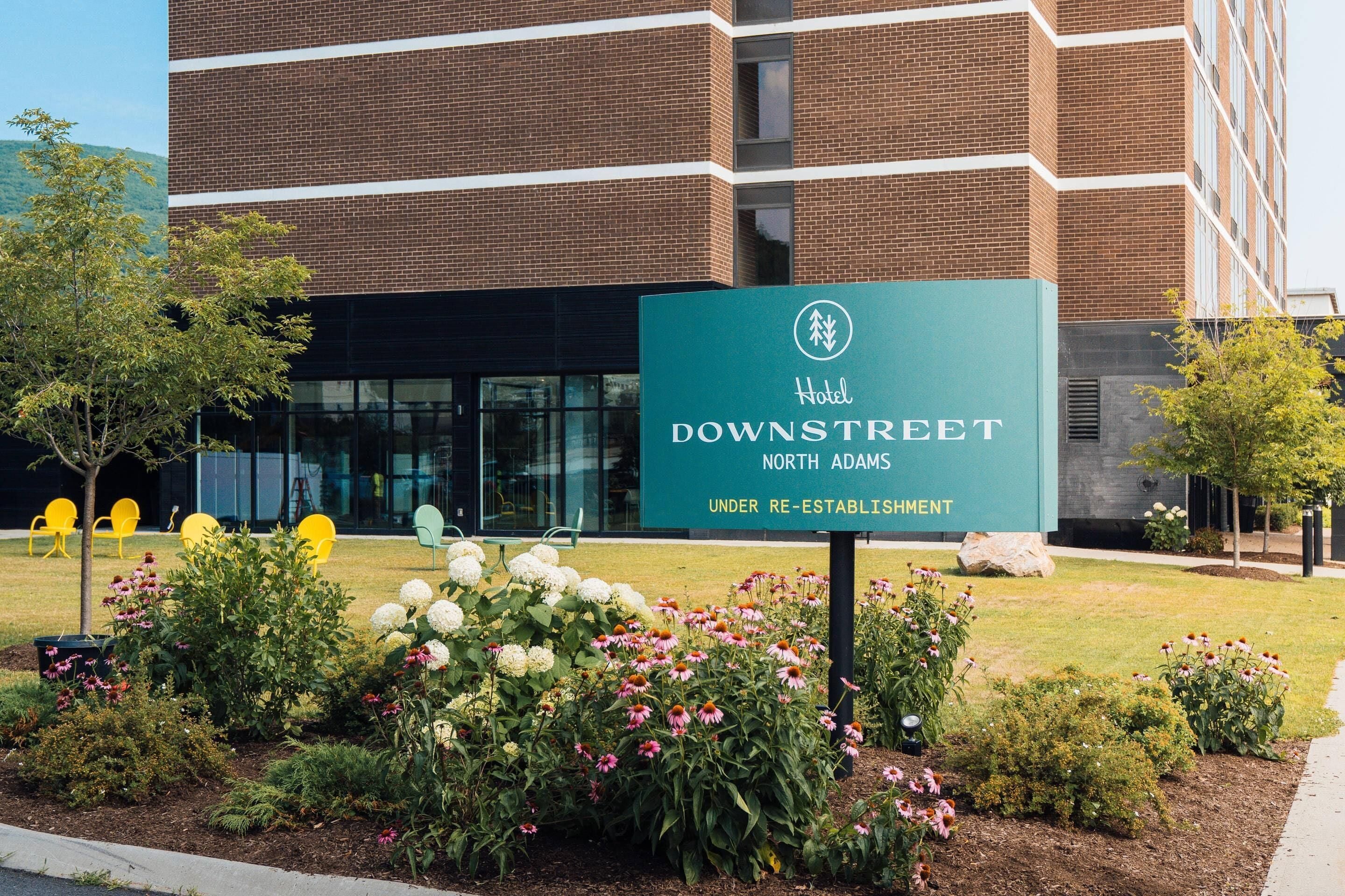 A hotel sign for 'Hotel Downstreet North Adams' with a modern brick building in the background.