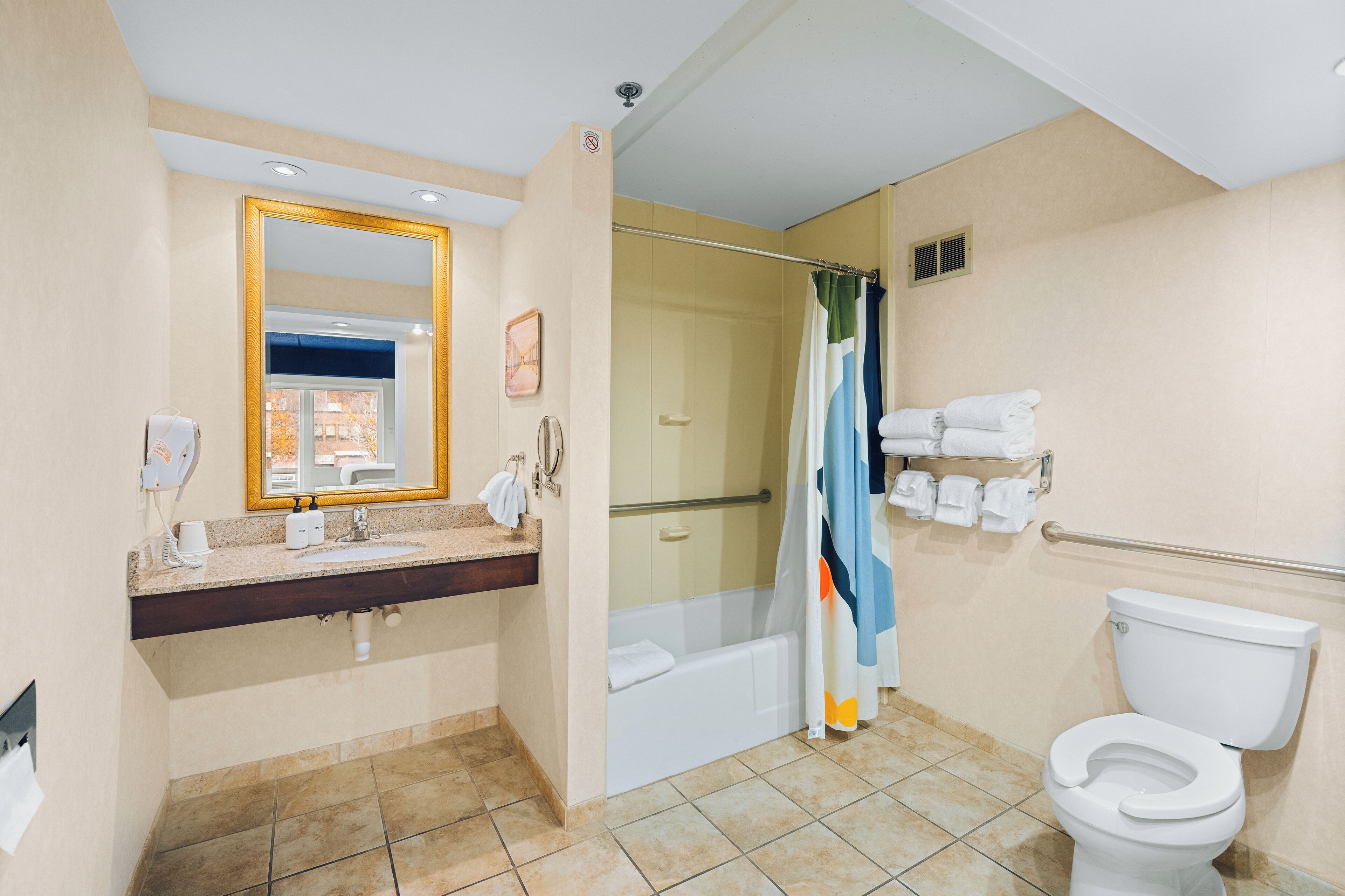 A bathroom with a shower, toilet, sink, and a large mirror.
