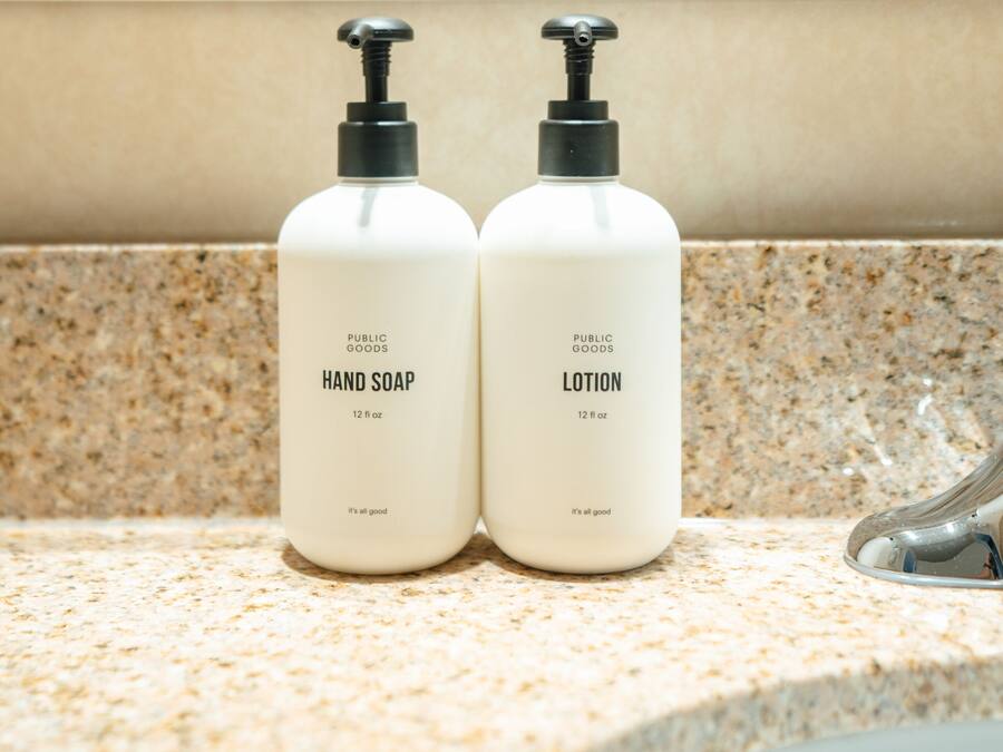 Two bottles of hand soap and lotion on a bathroom countertop.