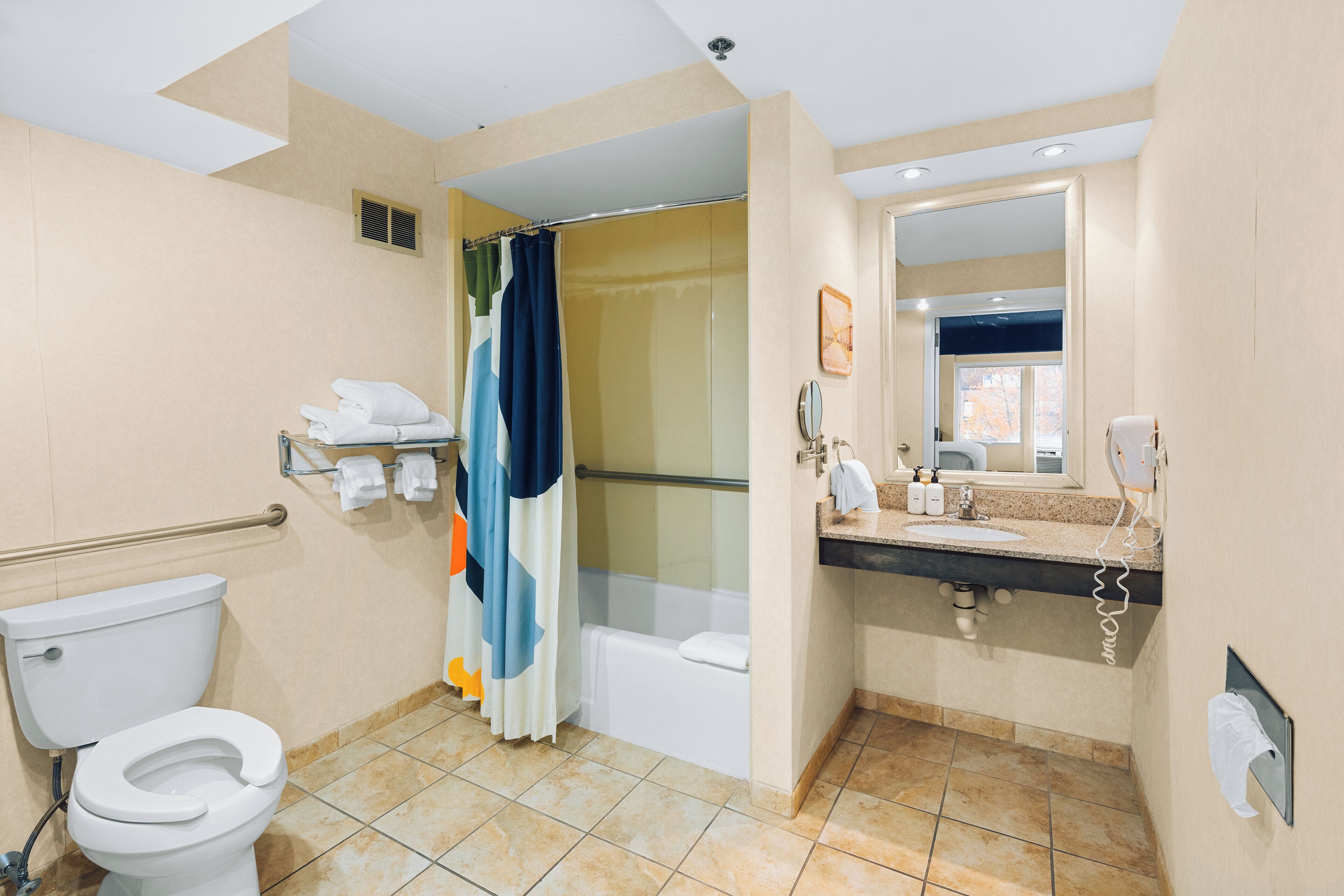 A bathroom with a toilet, shower, bathtub, and a sink with a mirror.