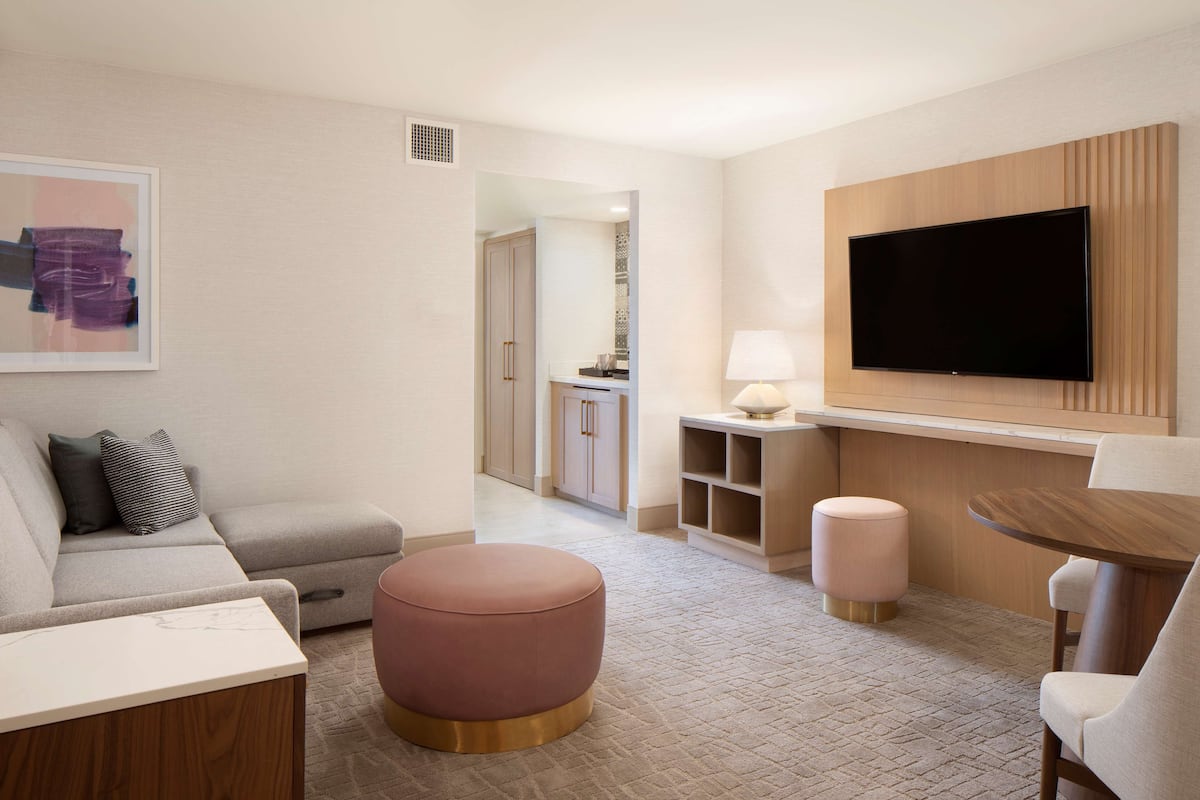 A modern living room with a sofa, ottoman, and a TV mounted on the wall.
