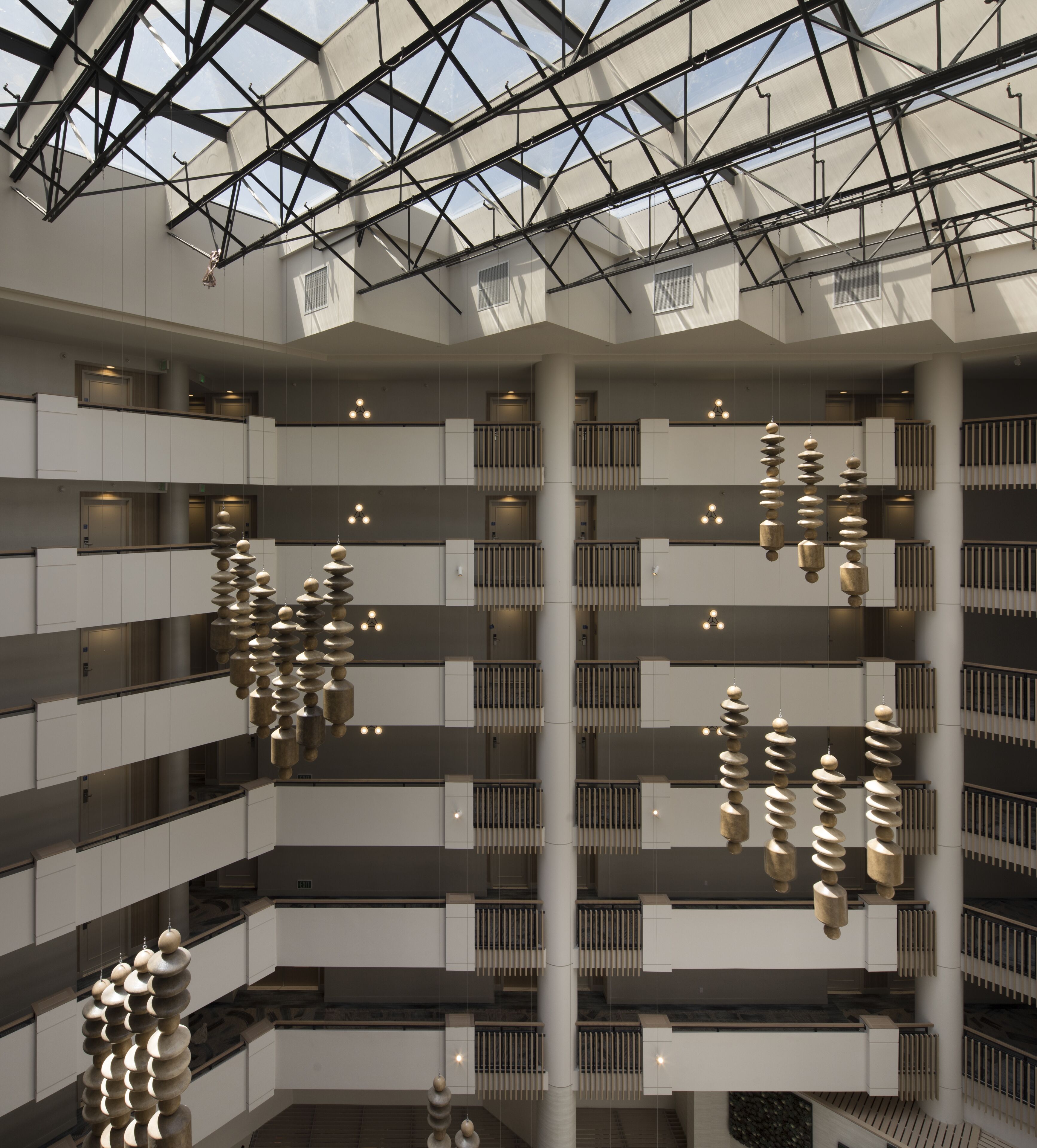 A multi-level atrium with a modern design, featuring a central open space with hanging spherical sculptures and a glass ceiling allowing natural light.
