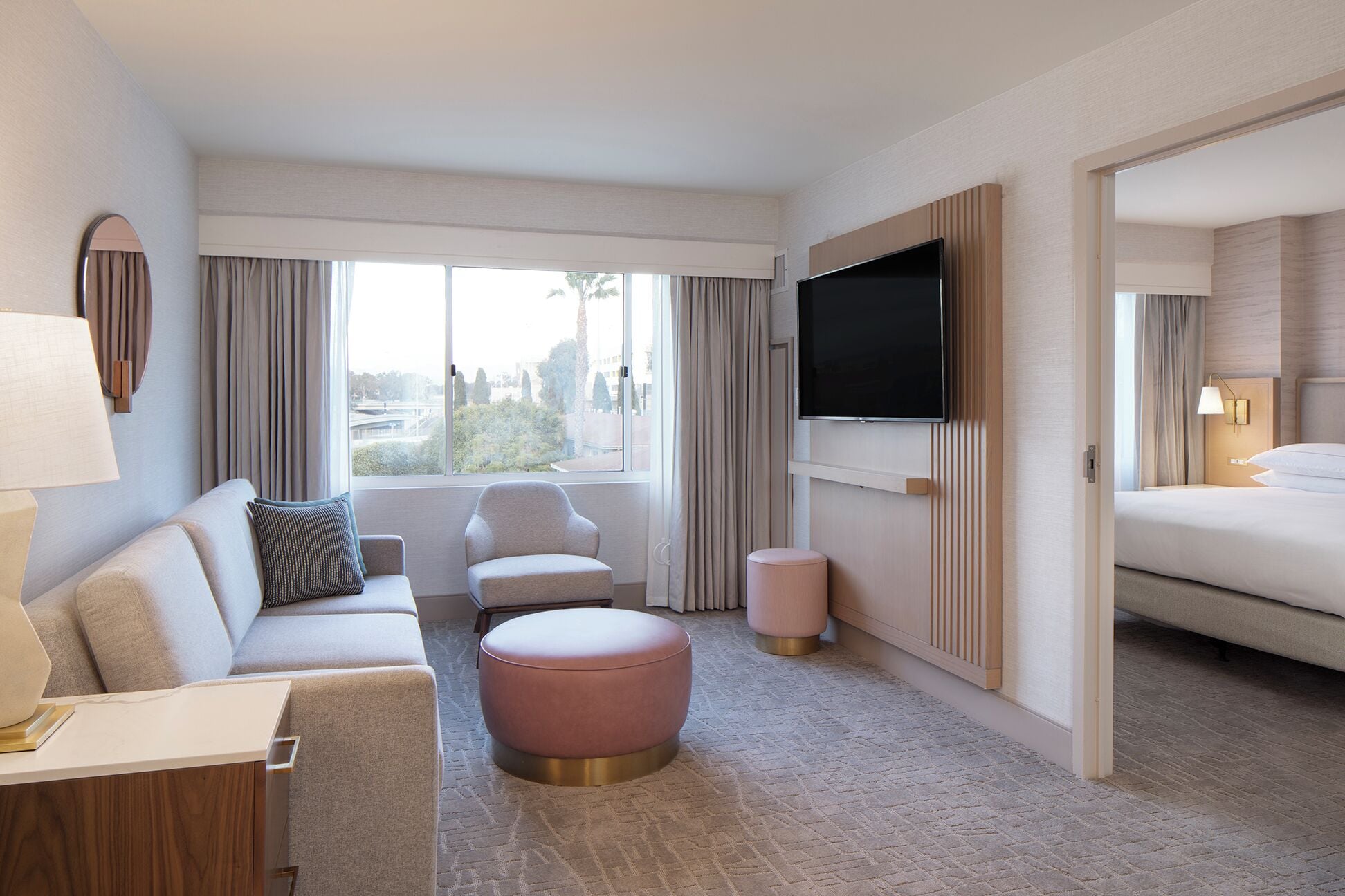 Une chambre d’hôtel moderne avec un canapé, un pouf et un lit.