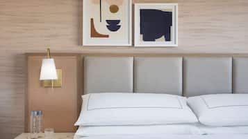 Een hotelkamer met een bed, een nachtkastje met een lamp en twee ingelijste abstracte kunstwerken aan de muur.
