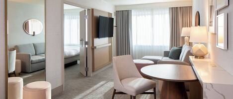 Una habitación de hotel con cama, sofá, mesa de comedor y televisor.