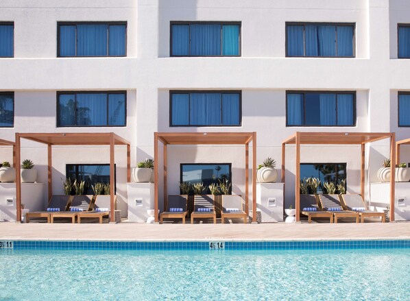 Una piscina al aire libre, sillones reclinables de piscina