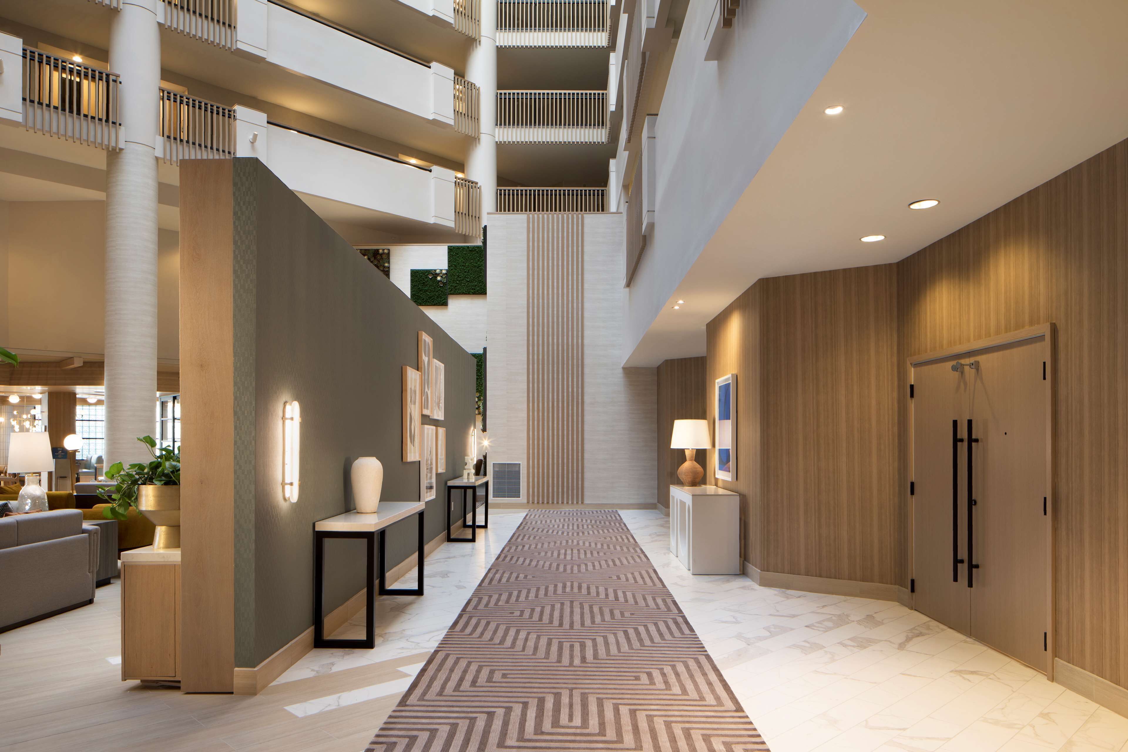 A spacious hotel lobby with a central staircase, multiple floors, and a modern design.