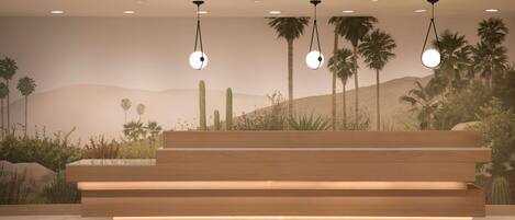 Una recepción con detalles de madera, iluminación empotrada y un mural con motivos desérticos de fondo.