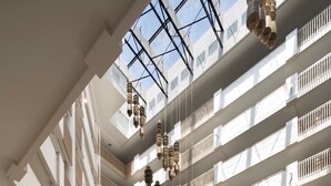A spacious atrium with multiple floors, a central seating area with sofas and chairs, and hanging pendant lights. - Hilton Santa Monica Hotel & Suites (Santa Monica)