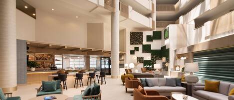 Un hall d’entrée spacieux, doté de plusieurs espaces de détente, d’un bar et d’un plafond haut avec un design moderne.