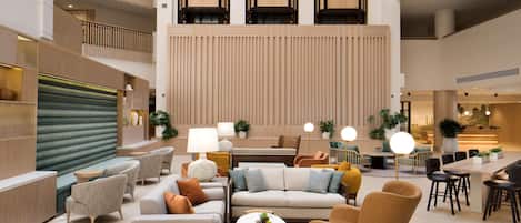 Eine geräumige Lobby mit mehreren Sitzbereichen, einer hohen Decke und einem modernen Design.
