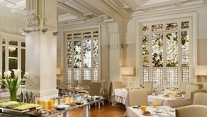 Un comedor de hotel con barra de desayuno tipo buffet, candelabros elegantes y ventanas amplias con paneles de vidrio decorativos.