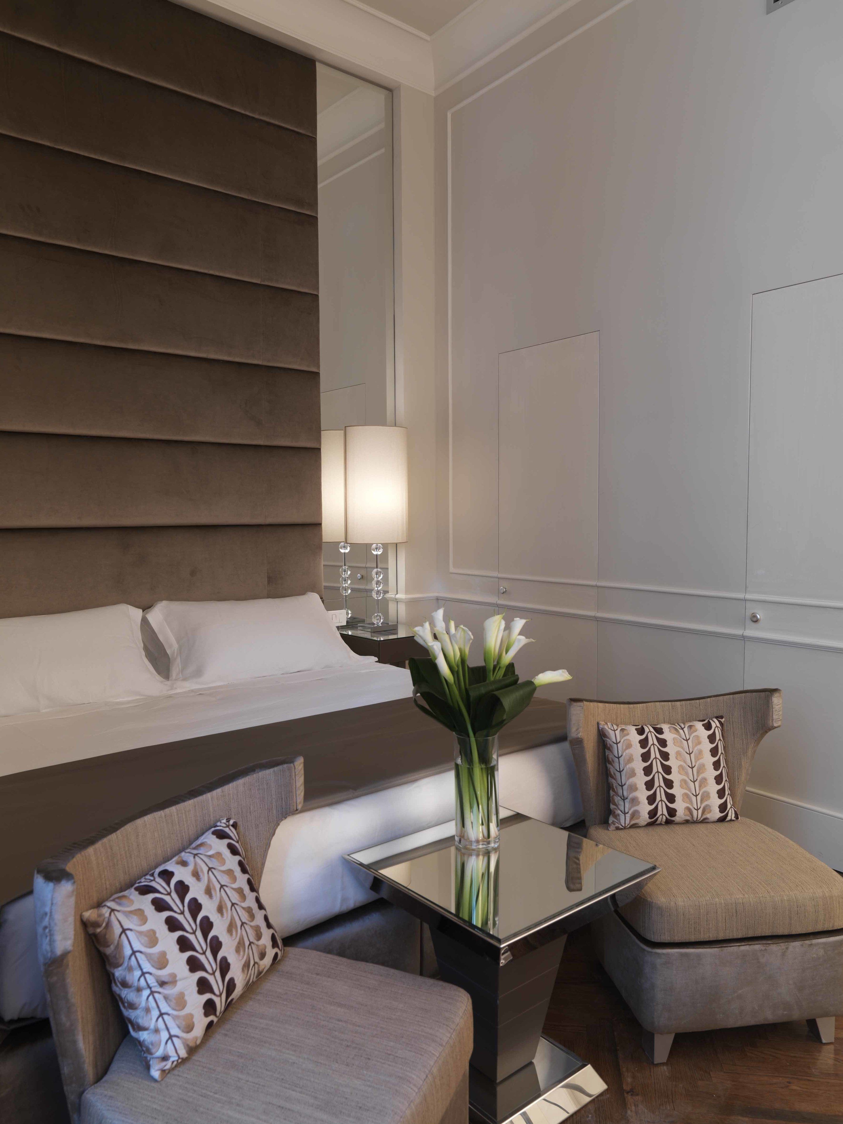Habitació d'hotel moderna amb un llit, un sofà, una taula petita i un ram de flors.