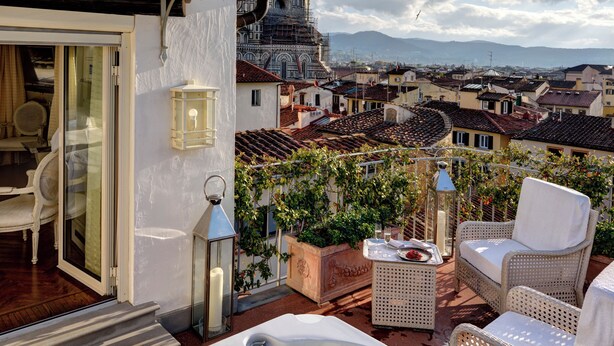 Terraza en la azotea con jacuzzi, sillas de mimbre y vistas a una cúpula histórica y al paisaje urbano.