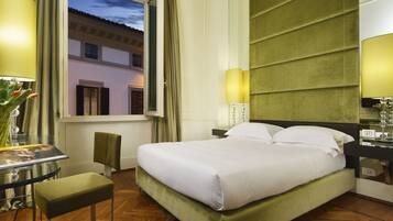 Una habitación de hotel con cama, escritorio, silla y ventana con cortinas.