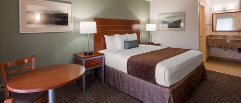 A hotel room with a bed, bedside tables, a desk, and chairs.