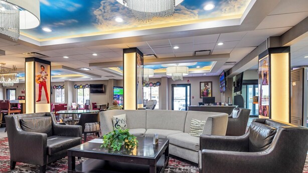 A spacious lobby with a modern design, featuring a large sofa, leather armchairs, and a coffee table.