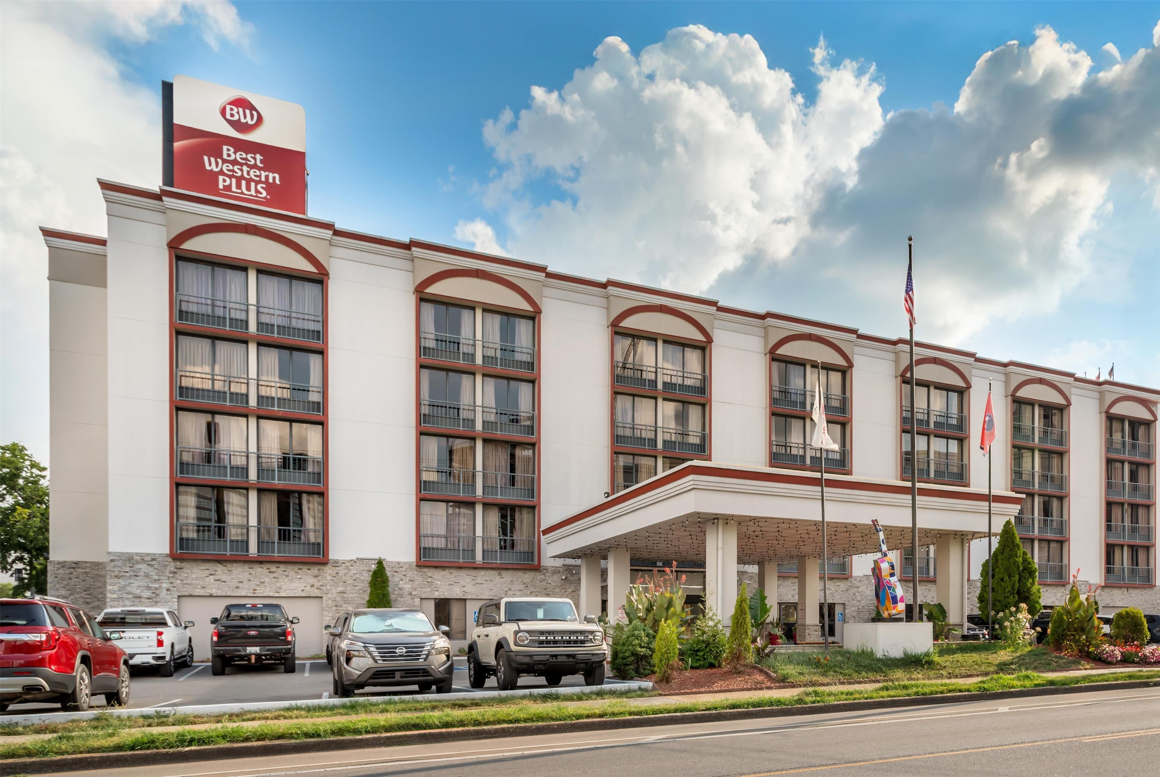 A hotel with a prominent 'Best Western Plus' sign, multiple parking spaces, and a landscaped entrance area.