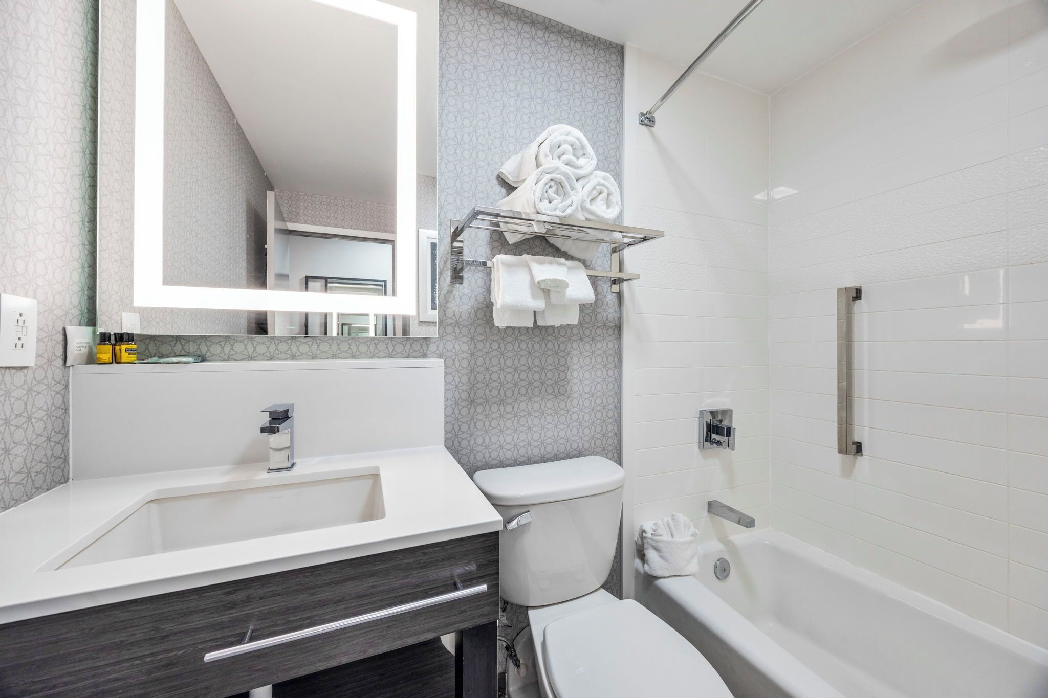 Ein modernes Badezimmer mit Waschbecken, dunklem Holzschrank, Toilette und Badewanne.