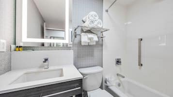 Un baño moderno con lavamanos blanco, tocador de madera oscura, inodoro y bañera.