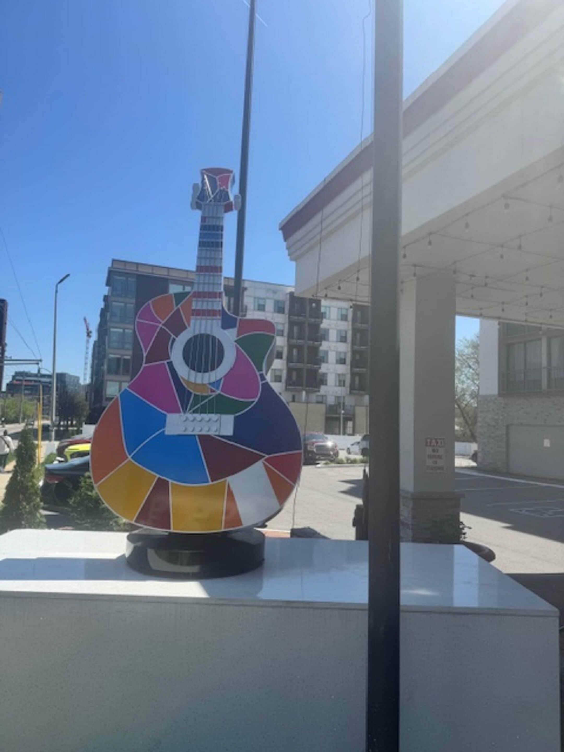 Una escultura de guitarra de colores sobre una acera.