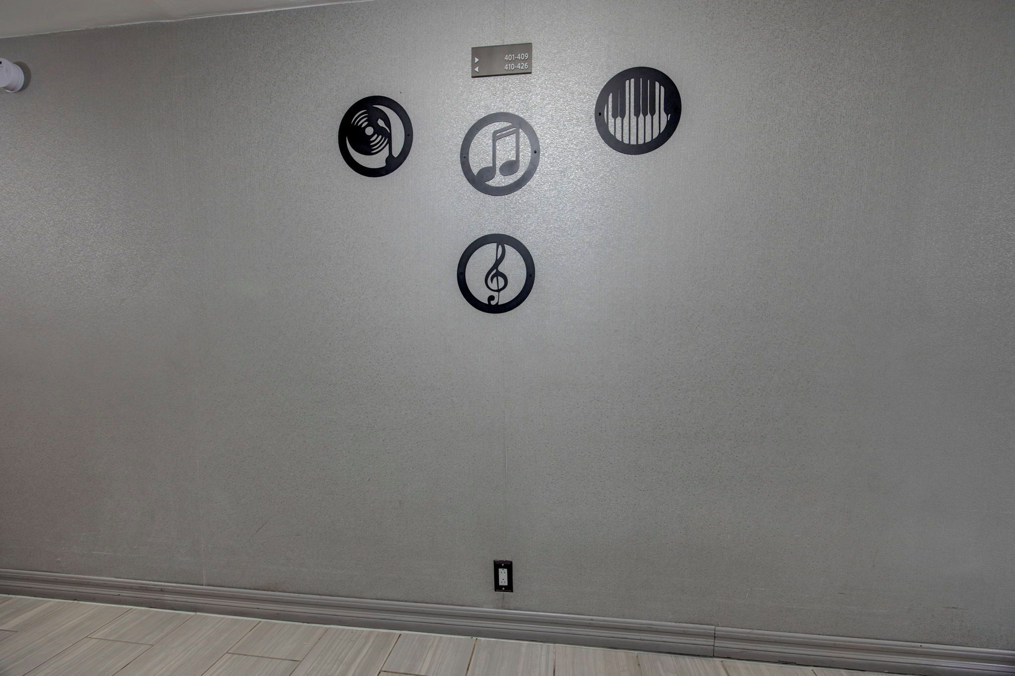 A wall with four black circular icons, each depicting different musical instruments.