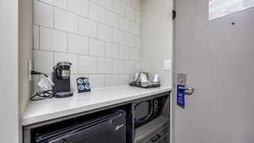 A compact kitchenette with a coffee maker, microwave, and a small refrigerator.