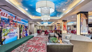 A hotel lobby with a red carpet, modern furniture, and a large chandelier.