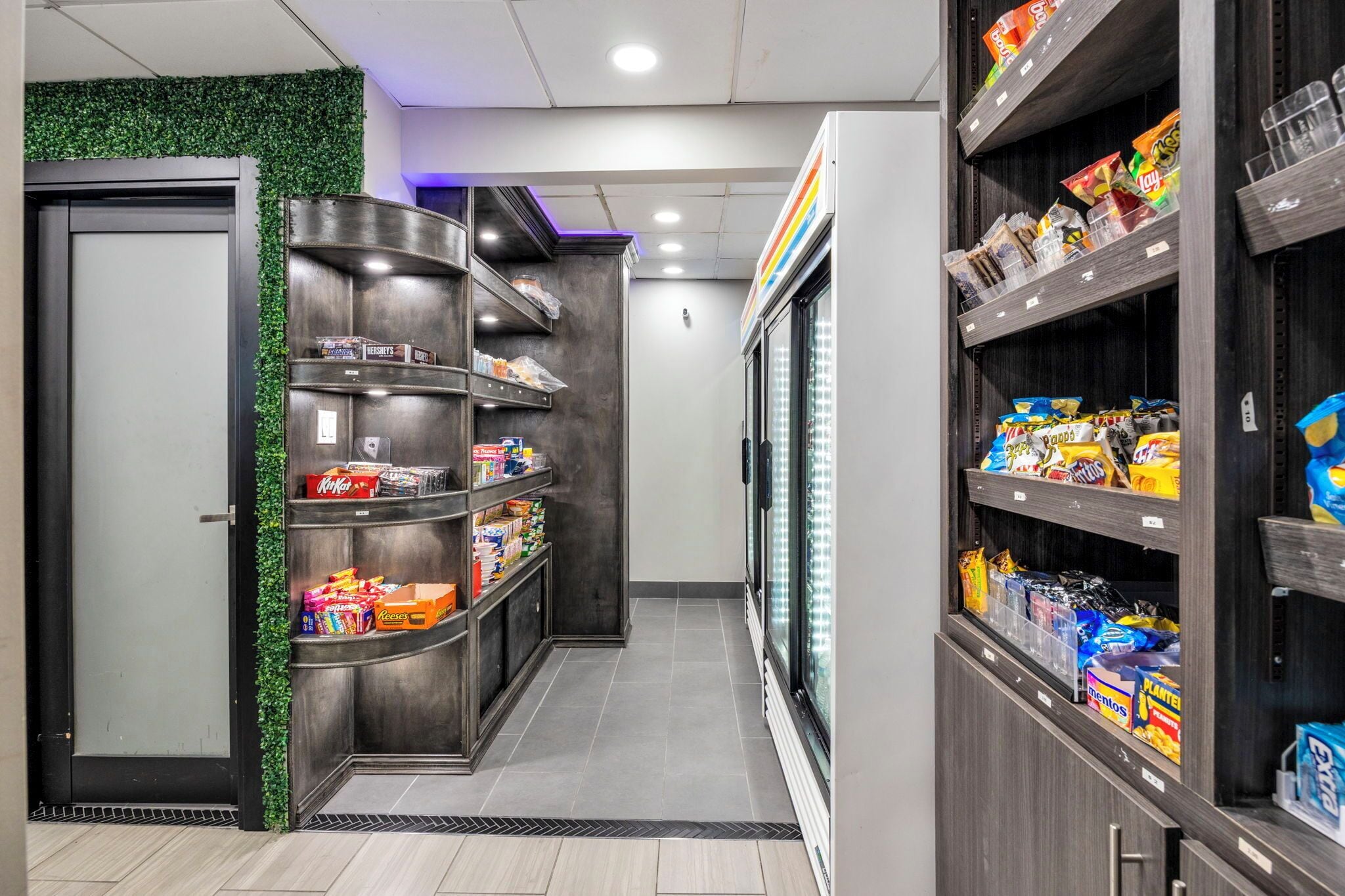 A corridor with shelves stocked with snacks and a refrigerated display.