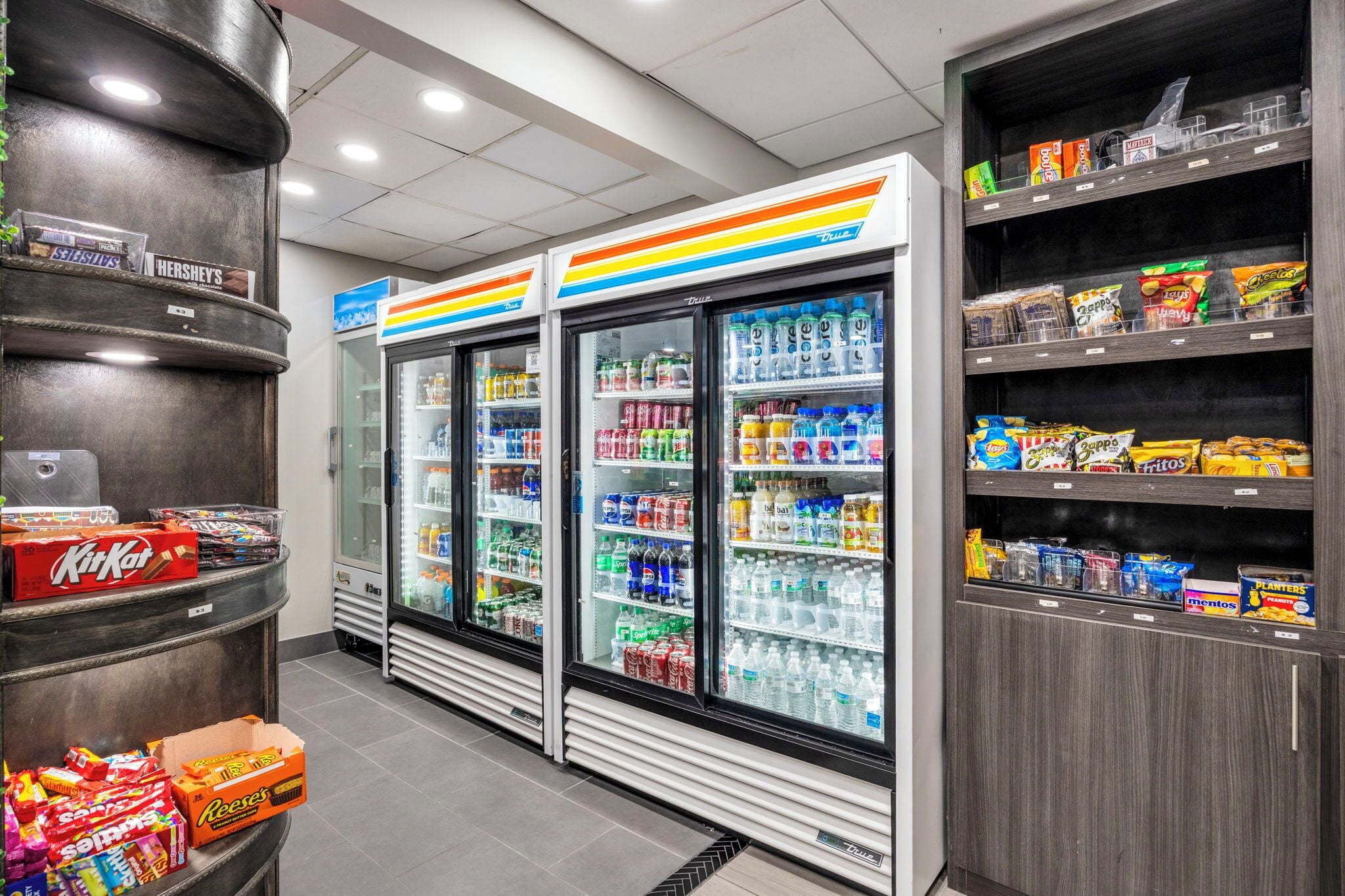 Ein Kiosk mit Kühlregalen für Getränke, Regalen voller Snacks und einer Auswahl an Süßigkeiten und Getränken.