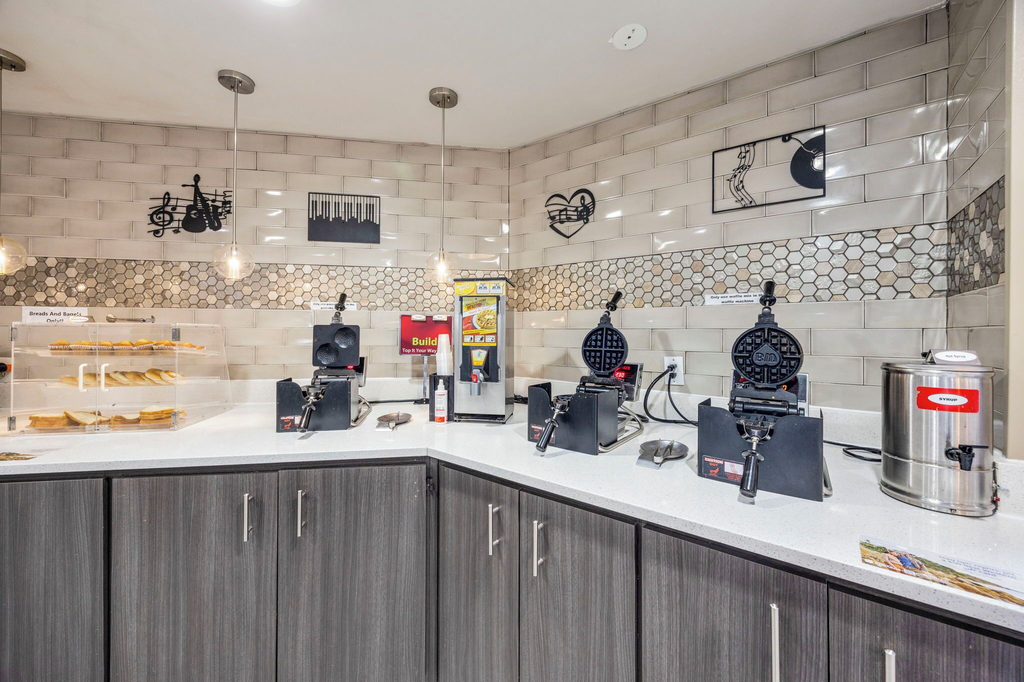 A kitchen area with a bread display, waffle maker, coffee machine, and a sign for 'Build Your Own'.