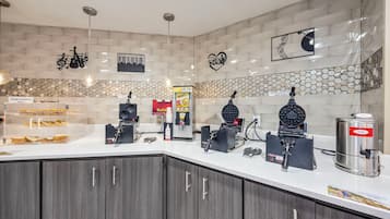 A kitchen area with a bread display, waffle maker, coffee machine, and a sign for 'Build Your Own'.