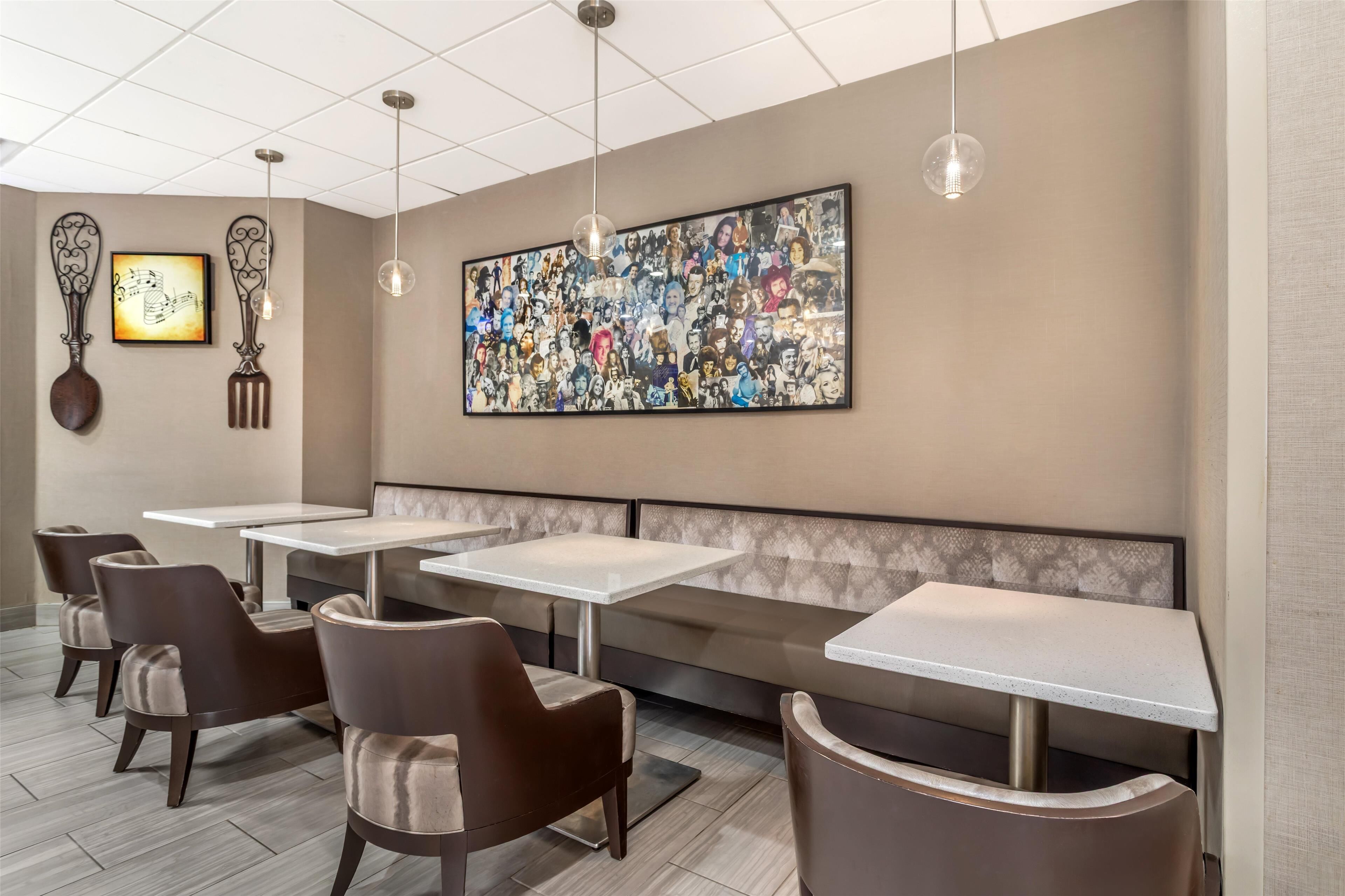 A modern restaurant interior with booth seating, a large wall mural, and pendant lighting.