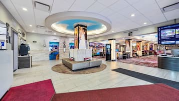 A hotel lobby with a reception desk, seating area, and a large digital screen displaying content.