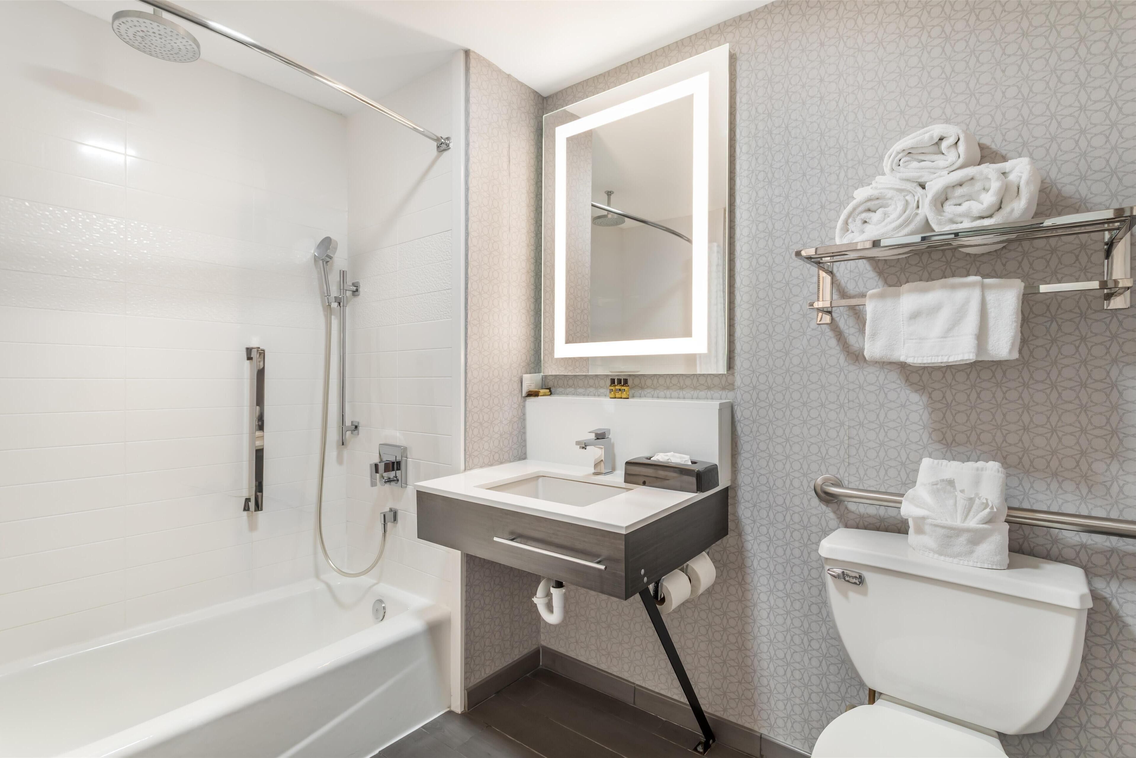 A modern bathroom with a bathtub, a sink, a toilet, and a towel rack.