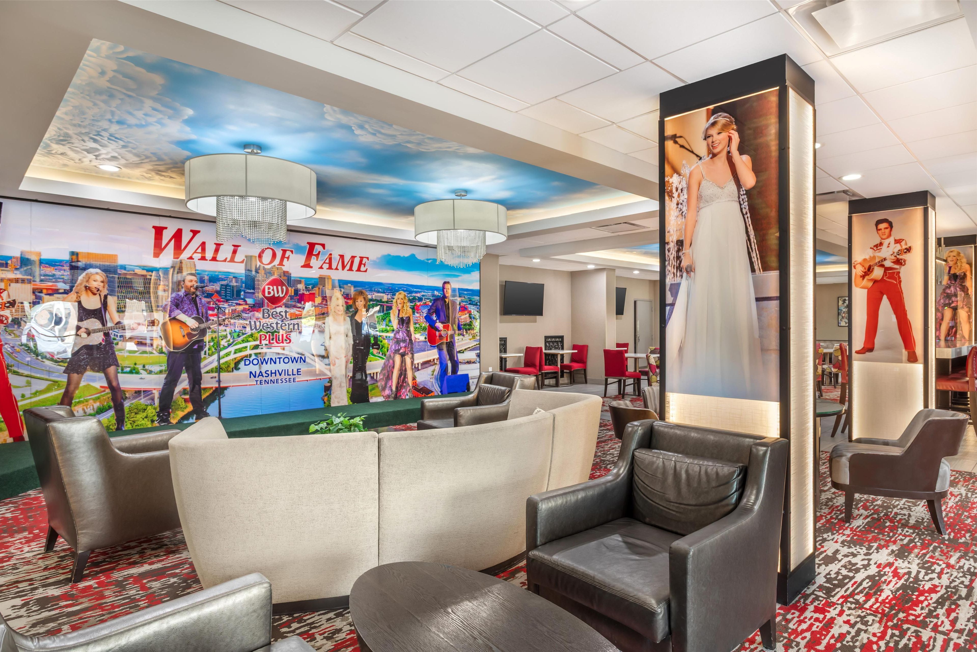 Hall d'albergo con un grande murale 'Wall of Fame', comodi posti a sedere e un lampadario moderno.